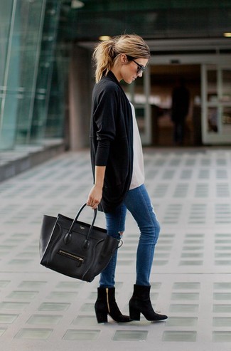 Девушка на улице в черном кардигане, с черной сумкой и в синих джинсах