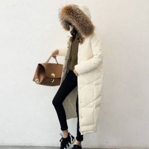 Длинный пуховик светлого оттенка, черные джинсы, коричневая сумка