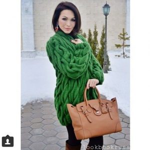 Девушка с короткой стрижкой с коричневой сумкой в руках и в теплом свитере объемного размера