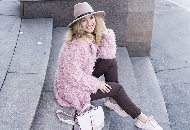 Девушка на ступеньках в розовом кардигане, с белой сумкой и в красивой шляпе