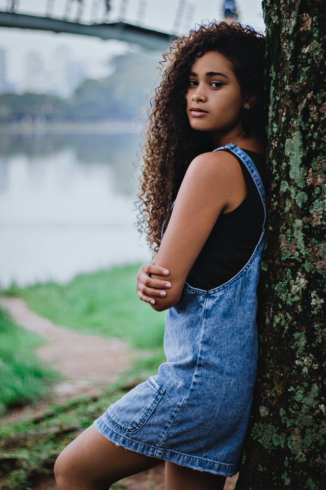 Девушка около дерева в джинсовом сарафане